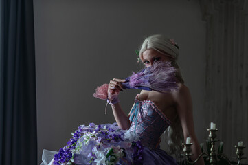 A girl dressed in the style of a Victorian boudoir, in a corset and crinoline of lilac color, in flowers