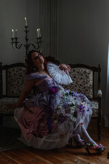 A girl dressed in the style of a Victorian boudoir, in a corset and crinoline of lilac color, in flowers