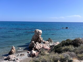 Aphrodite Beach with Stone Rocks in Aphrodite bay of Mediterranean sea water, blue sky in sunny day background, Petra tu Romiou, Cyprus