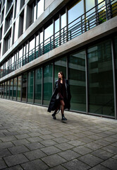Elegant woman running and jumping in front of an office building in Stuttgart, Germany