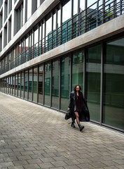 Elegant young woman walking outside modern office building in Stuttgart city
