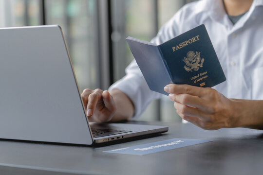 close up hand holding passport for online booking and buy ticket on laptop.