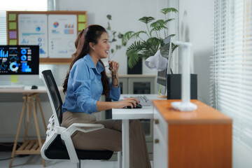 Businesswoman sitting at a modern desk in a bright office, working intently on a computer while holding eyeglasses and focusing on the screen, exemplifying professionalism and productivity