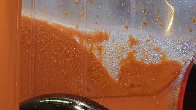 A shot of a Thai tea slurpee machine mixing. 