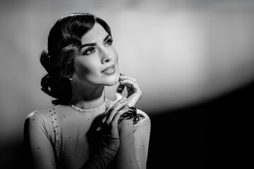 Monochrome styled photo of beautiful young fashionable lady posing. Girl in black and white retro portrait with Harcourt-style lighting and elegant wavy hairstyle