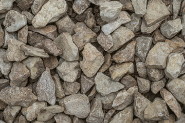 Pile of beige and light brown gravel stones close-up.