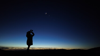 Fototapeta premium Amateur astronomer looking at the evening skies, observing planets, stars, Moon and other celestial objects with binoculars.