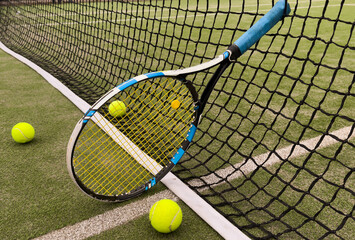 A tennis racket and new tennis ball on a tennis court