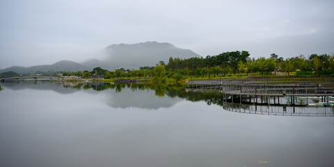 Obraz premium Sejong City, South Korea autumn landscape with soft reflections over a foggy pond at the National Sejong Arboretum on a calm morning—where mist and nature gently meet.