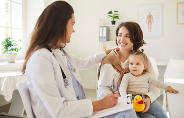 Young mother parent sitting with cute child baby and talking with smiling friendly pediatrician...