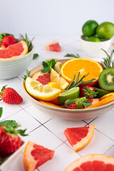 Close-up of fresh fruits and citrus: orange, lemon, lime, grapefruit, kiwi and strawberries in bowls on white background. Concept of health, freshness and natural eating