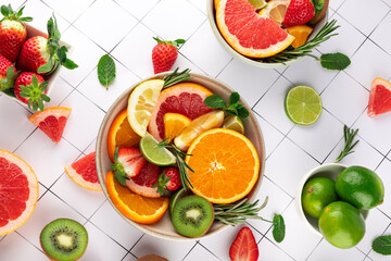 Colorful summer still life with citrus fruits, strawberries, and kiwi. Top view on a light background. Perfect for healthy eating. Concept of summer and natural diet