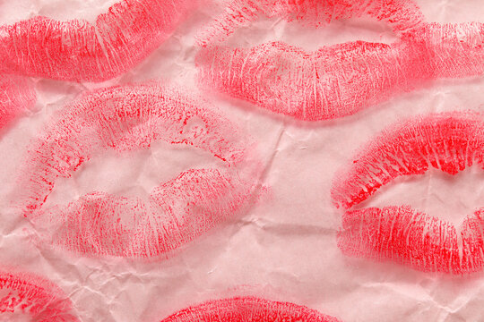 Lipstick kiss marks on pink paper sheet, closeup