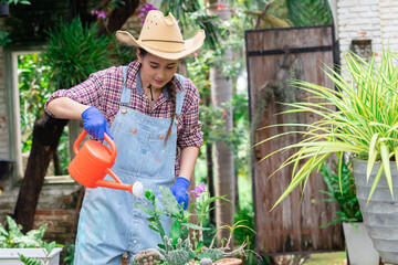 Asian gardening women planting flowers in garden wearing hand gloves, happy female watering nursery...