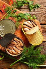Canned smoked sprats with parsley and dill on wooden table