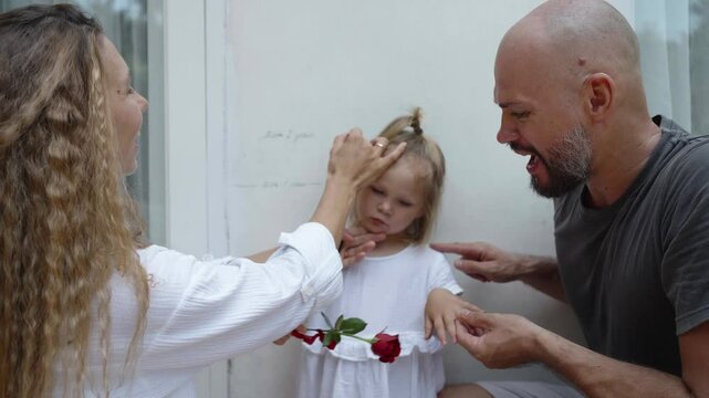 Parents measure the height of their daughter by drawing the mark on the wall of their house. Father and mother enjoy how quick growing their child. Home family activity