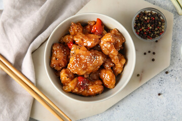 Tasty sweet and sour chicken in bowl with spices on light background, closeup