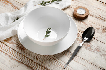 Beautiful table setting and branches on light wooden background, closeup