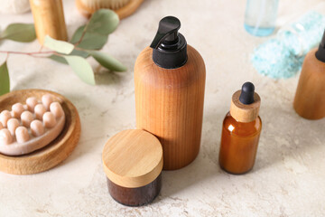 Bottles of cosmetic products, massage soap and cream on light background, closeup