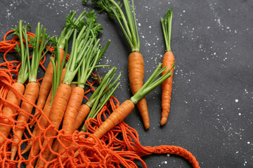 Fresh carrots in wicker bag on black grunge background