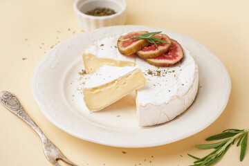 Plate with pieces of tasty Camembert cheese on yellow background