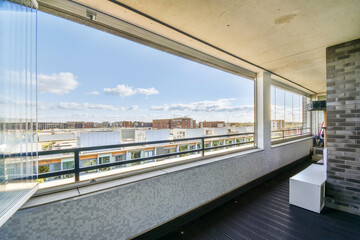 A spacious balcony showcasing a panoramic view of urban buildings and a clear sky, inviting a sense...
