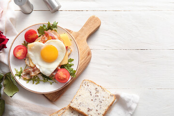 Plate with tasty fried egg, toasts, tomatoes and arugula on light wooden background