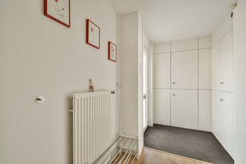 A clean and bright indoor entryway featuring simple white walls, framed artwork, and stylish storage. The serene atmosphere creates a welcoming feel.