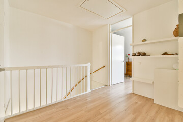 A spacious and well-lit interior hallway featuring wooden flooring, white walls, and an open door leading to another room, creating an inviting atmosphere.