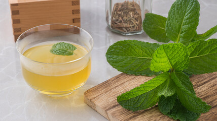 Cup with mint tea and mint plant on cutting wood