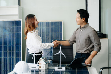 Two Asian engineers collaborate on a solar and wind energy project, discussing innovation and...