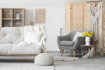 Interior of stylish living room with sofa, coffee table and vase of narcissus flowers