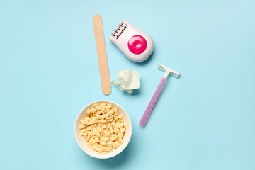 Modern epilator with stick, wax and razor on blue background
