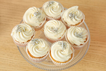 Dessert stand with tasty white cupcakes for birthday party on wooden table