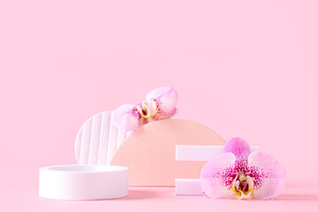 Decorative podiums with beautiful orchid flowers on pink background