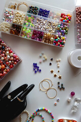 Hand figurine, colorful friendship bracelets, necklaces, various beads and DIY supplies on the table. Making jewelry at home. Flat lay.
