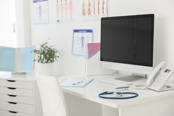 Stethoscope, computer and clipboard on desk in doctor's office
