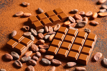 Sweet chocolate with cocoa beans and powder on dark background