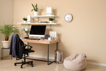 Stylish interior of office with workplace, modern computer and armchair