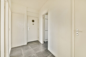 A clean and bright hallway featuring white walls and gray tiled floor, exemplifying modern minimalist design.