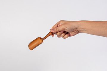 Brown plastic spoon in hand, isolated on white background