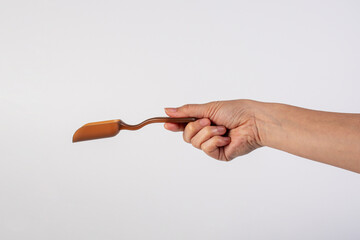 Brown plastic measuring spoon in hand, isolated on white background