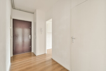 A spacious modern hallway featuring a clean aesthetic with white walls and wooden flooring, exuding minimalistic charm and functionality.