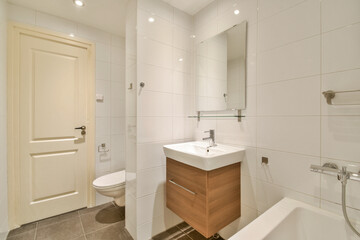 Stylish modern bathroom featuring sleek fixtures, clean lines, and minimalist design. The space includes a wooden vanity and contemporary tile work.