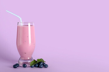 Glass of fresh blueberry smoothie with mint and berries on lilac background