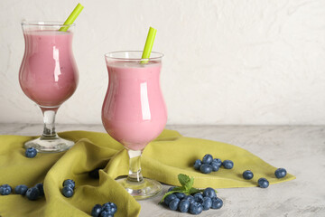 Glasses of fresh blueberry smoothie with mint and berries on white background