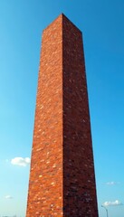 Tall brick structure dominates a clear, bright sky , facade, clear, perspective