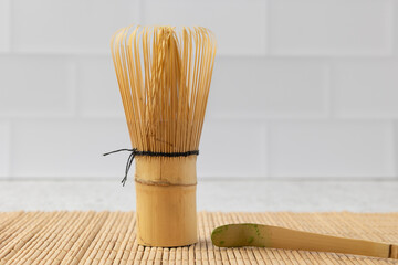 Bamboo whisk and matcha spoon resting on a bamboo mat in a modern kitchen