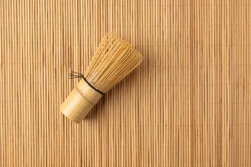 Bamboo whisk or chasen lying on a bamboo mat for preparing matcha tea