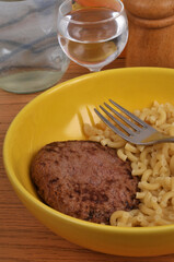 Assiette avec un steak haché accompagné de coquillettes avec une fourchette en gros plan